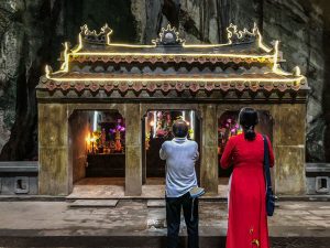 Betende Asiaten vor einem kleinen Tempel