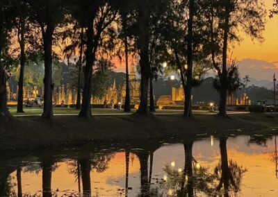 Park bei Sonnenuntergang mit Tempelruinen hinter Bäumen